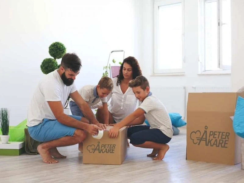 En familj packar flyttkartonger märkta Peter Åkare tillsammans.